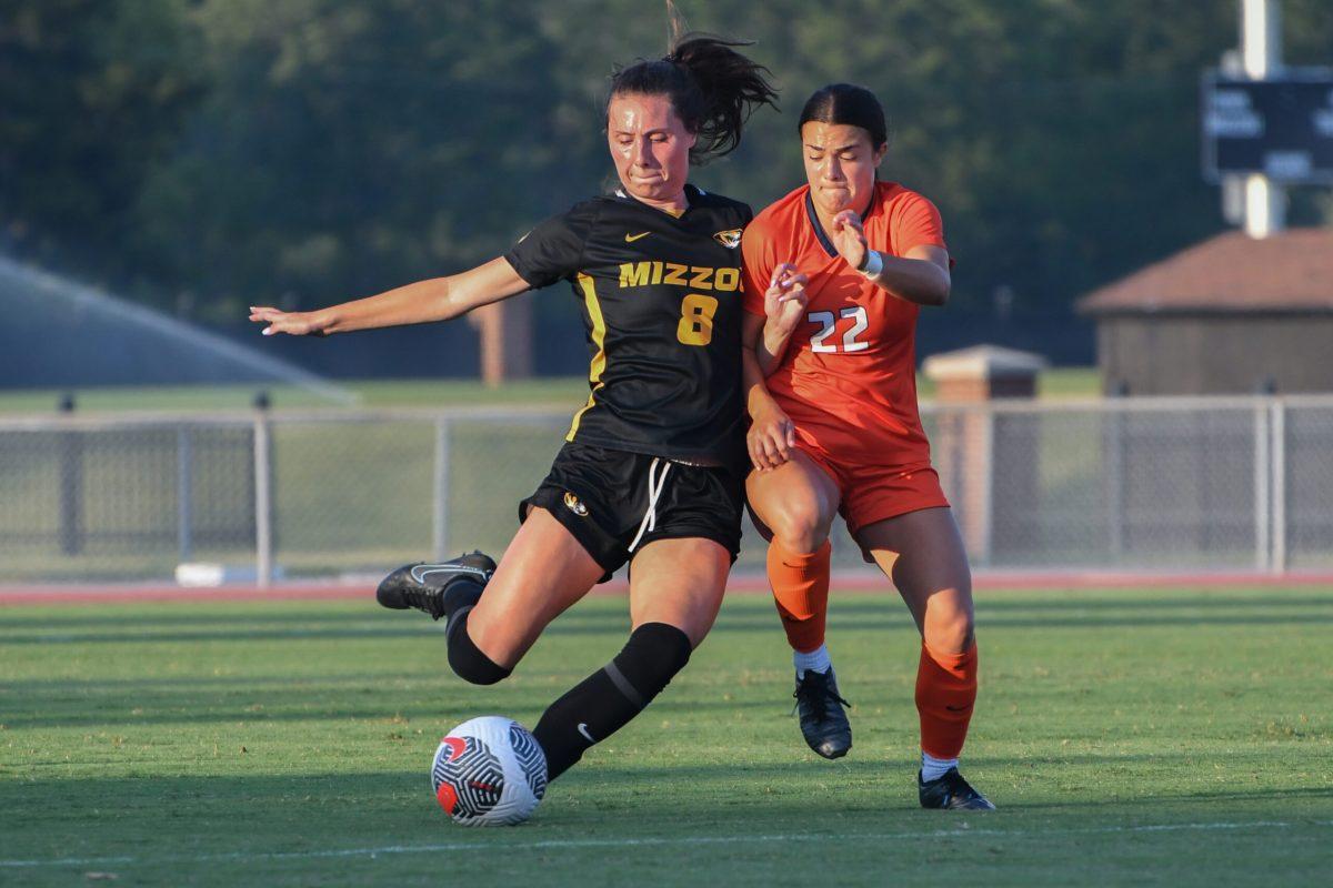 A Missouri soccer player kicks a ball, guarded by an Illinois soccer player